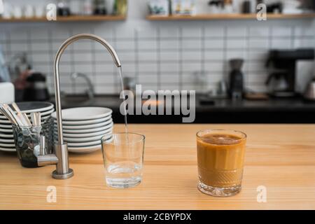 de l'eau coule d'un robinet dans un verre Banque D'Images