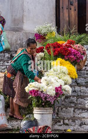 Une femme maya Quiche vend des fleurs sur le marché des fleurs sur les marches mayas pré-hispanique devant l'église de Santo Tomas à Chichichastenango, Gua Banque D'Images