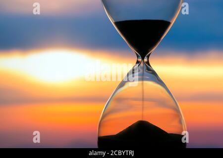 HourGlass sur le fond d'un coucher de soleil. La valeur du temps dans la vie. Une éternité. Banque D'Images