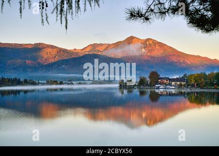 Le village et les montagnes au bord de la rivière reflètent l'eau dans la matinée brumeuse au lac Wolfgang, en Autriche. Banque D'Images