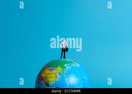 Miniature People concept - un homme d'affaires désespéré debout sur le globe Banque D'Images