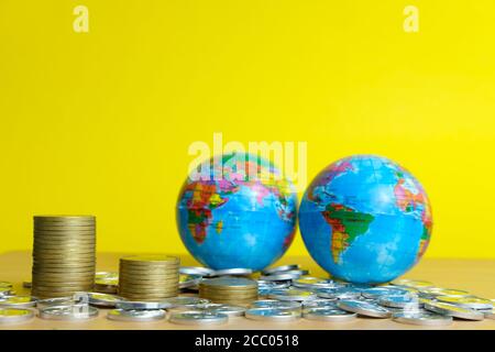 Concept commercial et financier mondial - diminution de la pile de pièces devant le globe terrestre Banque D'Images