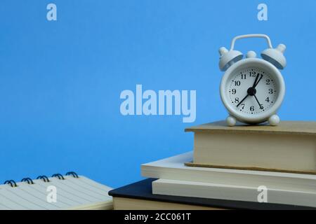 Concept de charge de travail de bureau : pile de livres avec horloge activée le haut Banque D'Images