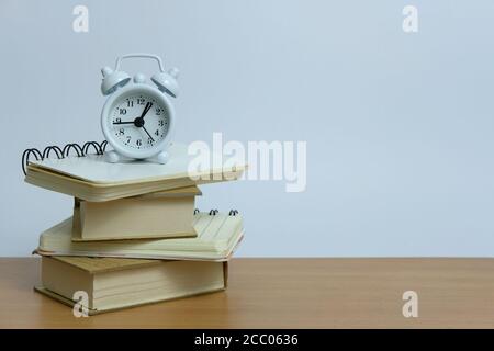 Concept de charge de travail de bureau : pile de livres avec horloge activée le haut Banque D'Images
