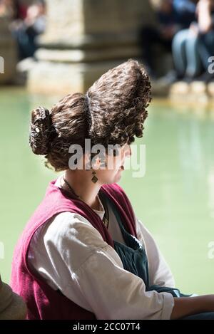 Coiffure romaine féminine complexe de classe supérieure portée par un réacteur féminin assis sur le bord du Grand bain, Bath, Angleterre. Copier l'espace. Vue latérale. Banque D'Images