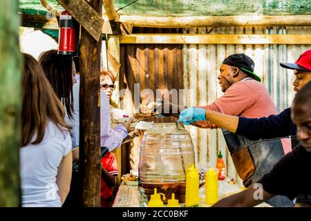 Johannesburg, Afrique du Sud - 24 mai 2015: African Male vendor de nourriture à emporter dans une cabine extérieure sur le marché des agriculteurs Banque D'Images