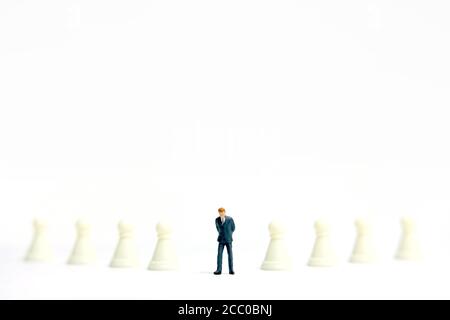 Concept de stratégie d'affaires miniature - homme d'affaires debout entre échecs fanés ligne de pièce Banque D'Images