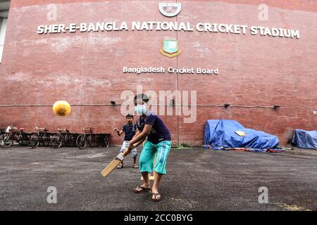 Dhaka, Bangladesh. 16 août 2020. Un gamin local portant un masque joue au cricket de rue le long du stade de Dhaka. Le Bangladesh devrait revenir au cricket international avec la tournée du Sri Lanka, pour une série d'essais de trois matchs en octobre-novembre.l'équipe se rendra toutefois dans la nation insulaire un mois avant le début de la série, en septembre. Crédit : SOPA Images Limited/Alamy Live News Banque D'Images