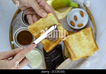 Grand choix de plats pour le petit déjeuner sur une table avec toasts, chocolat, banane, yaourt, beurre de chocolat, noix servies avec du café vu d'en haut Banque D'Images