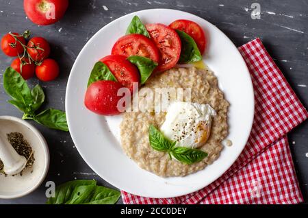 flocons d'avoine avec œuf poché, tomates et basilic. repas de nutrition frais et savoureux. nourriture saine pour le petit déjeuner Banque D'Images