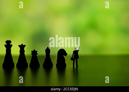 Photo conceptuelle de la stratégie d'affaires - Silhouette de l'homme d'affaires miniature pointant à l'envers, debout devant la rangée de pièces d'échecs Banque D'Images