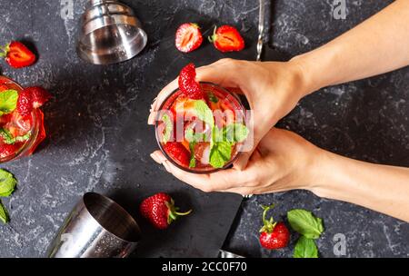Les mains des femmes ont un verre de mojito de fraise sur fond de pierre noire. Vue de dessus Banque D'Images