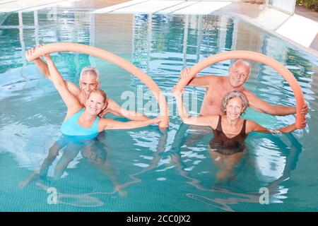 Le groupe senior fait de l'aqua fitness comme entraînement de dos avec la natation nouilles dans la piscine Banque D'Images