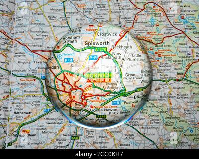 Gros plan d'une loupe en forme de dôme sur une page d'une carte de l'atlas routier britannique, avec la région de Norwich en Angleterre élargie pour une vue plus rapprochée. Banque D'Images