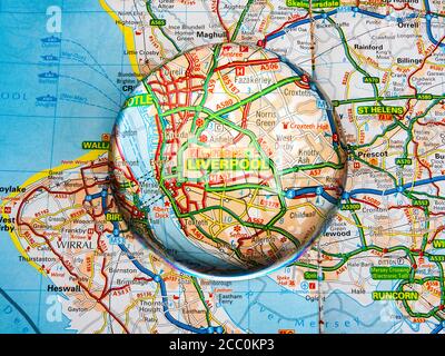 Gros plan d'une loupe en forme de dôme sur une page d'une carte de l'atlas routier britannique, avec la région de Liverpool en Angleterre agrandie pour une vue plus rapprochée. Banque D'Images