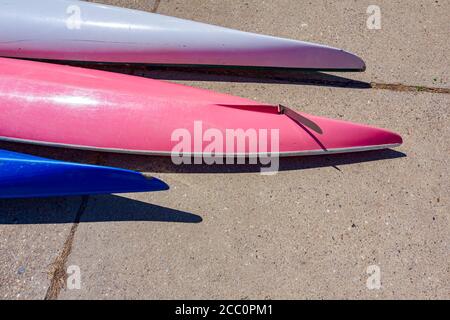 Rangée de kayaks colorés à l'envers placés sur la côte en béton au bord de la rivière. Banque D'Images