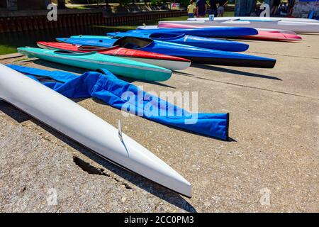 Rangée de kayaks en plastique coloré sont placés sur la côte en béton à côté de la rivière. Banque D'Images