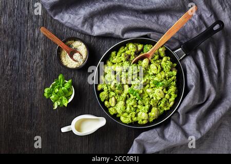 Gnocchi italien aux fleurons de brocoli avec pesto au basilic et sauce crémeuse au fromage dans une poêle, plat, vue horizontale d'en haut Banque D'Images