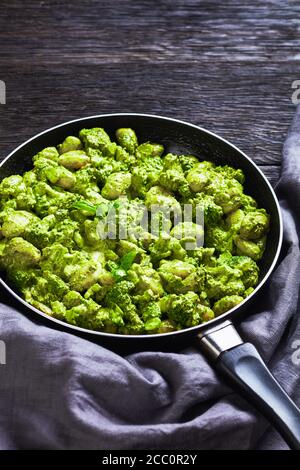 Gnocchi italien aux fleurons de brocoli avec pesto de basilic et sauce crémeuse au fromage dans une poêle, vue de dessus en gros plan Banque D'Images