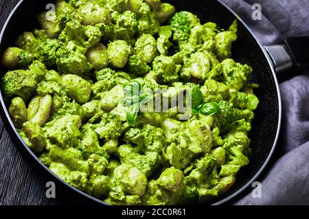 Gnocchi italien aux fleurons de brocoli avec pesto de basilic et sauce crémeuse au fromage dans une poêle, vue de dessus en gros plan, horizontale Banque D'Images