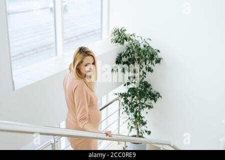 La jeune femme enceinte descend les escaliers après un rendez-vous avec un médecin à l'hôpital de maternité. Banque D'Images