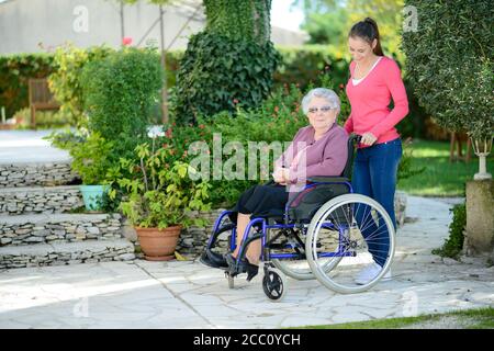 Jeune femme gaie dans un jardin de maison de retraite avec une femme âgée. Banque D'Images