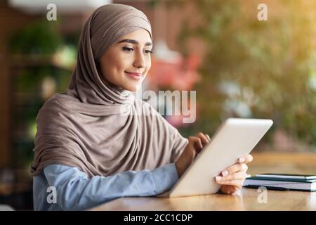 Belle femme musulmane blogueur travaillant au café, en utilisant une tablette numérique Banque D'Images