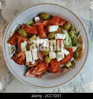 Salade grecque dans un bol profond. Tomates, concombres, poivrons, olives, feta, huile d'olive. Vue de dessus Banque D'Images