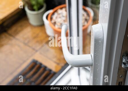 Foyer peu profond d'une porte de patio en UPVC récemment installée, vue ouverte menant à une zone de patio humide à l'arrière d'une maison. Banque D'Images