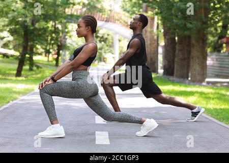 Style de vie sportif. Black Fitness couple en travaillant ensemble dans le parc, les muscles d'étirement Banque D'Images