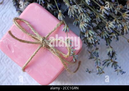 Deux barres de savon artisanal rose nouées avec des fleurs de ficelle et de lavande sur fond de bois blanc. Mise au point sélective, espace de copie Banque D'Images