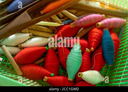 Vue de dessus fils colorés sur bobine et bobines en bois vides dans panier en plastique. Fils dans l'outil de navette de tissage. Outils à tisser en tissu textile. Équipement Banque D'Images