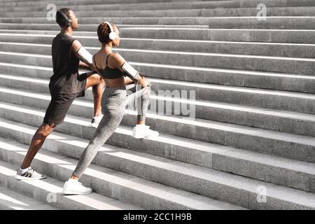 Couple Noir motivé réchauffant les muscles avant de faire du jogging à l'extérieur Escaliers urbains Banque D'Images