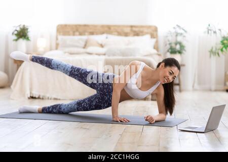 Formation en ligne. Asian Girl faisant du sport devant un ordinateur portable à la maison Banque D'Images
