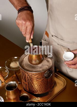 Café turc traditionnel infusé dans du sable chauffé. Processus de préparation par un barista. Banque D'Images