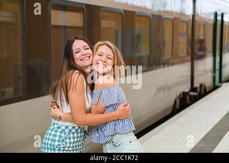 De jeunes femmes heureuses se tiennent sur la plate-forme de la gare Banque D'Images