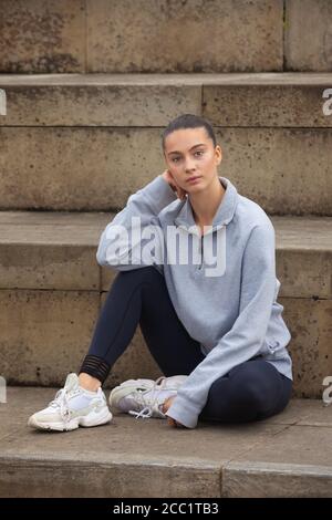 Une jeune femme sportive portant des vêtements de sport debout devant un ensemble de marches, prête pour l'exercice. Banque D'Images