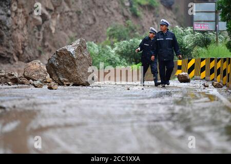 (200817) -- LONGNAN, le 17 août 2020 (Xinhua) -- les policiers vérifient le site d'un glissement de terrain sur une route nationale à Longnan City, dans la province de Gansu, dans le nord-ouest de la Chine, le 17 août 2020. Les pluies torrentielles d'une semaine dans la province de Gansu ont conduit à un affluent du fleuve Yangtze qui s'écoule au-dessus du niveau de danger alors que les autorités locales combattent diverses catastrophes provoquées par la pluie, notamment des torrents de montagne, des glissements de terrain et des coulées de boue. Lundi, les pluies ont endommagé 3,303 km de routes dans la ville de Longnan, perturbant la circulation sur 497 routes. Plus de 38,000 personnes ont été déplacées à Longnan. (Réceptacle Xinhua/Chen) Banque D'Images