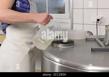 Allemagne, Baden Wuerttemberg, Mid adult woman pouring water en laboratoire de remplissage Banque D'Images