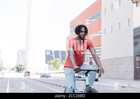 Vue latérale d'un cycliste afro-américain à vélo remblai ensoleillé Banque D'Images