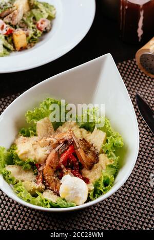 Salade césar aux crevettes sur une plaque blanche Banque D'Images