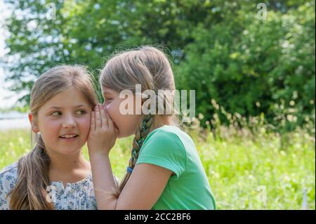 Germany, Bavaria, Munich, Girl whispering dans une autre oreille filles Banque D'Images