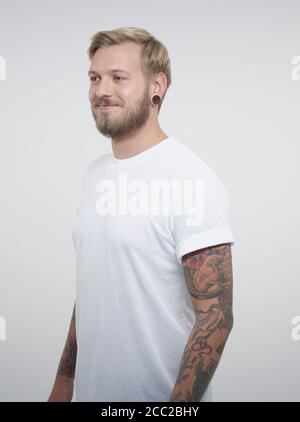 Jeune homme aux tatouages against white background, smiling Banque D'Images