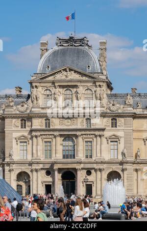 Musée du Louvre Paris avec des visiteurs à la lumière du soleil. Les gens qui se tiennent dans la file ou se détendent. Banque D'Images