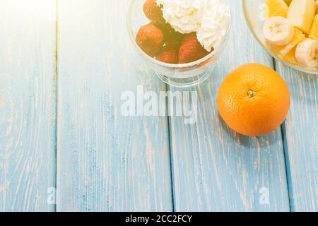 Petit déjeuner d'été : baies, pomme de fruit, fraise, orange, banane. Table bleu clair. Banque D'Images