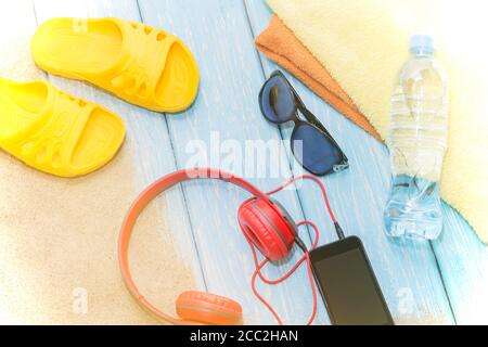 Bouteille d'eau et serviettes brillantes, ardoise jaune sur fond bleu et lunettes de soleil. Copier l'espace. Banque D'Images