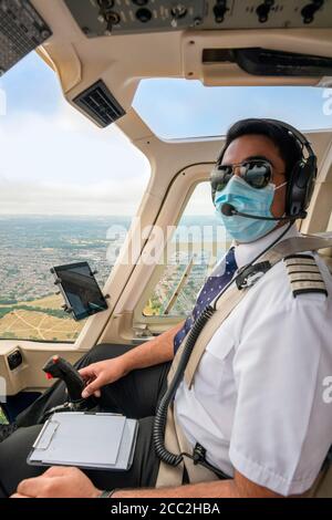 Portrait vertical d'un pilote portant un masque facial volant un hélicoptère au-dessus du sud-est de Londres. Banque D'Images