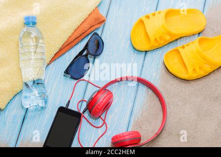 Bouteille d'eau et serviettes brillantes, ardoise jaune sur fond bleu et lunettes de soleil. Copier l'espace. Banque D'Images