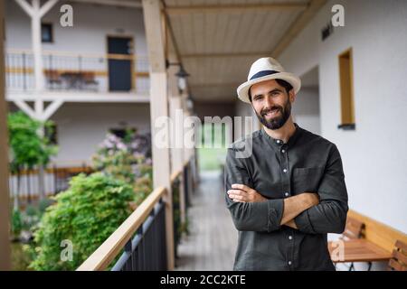 Jeune homme debout à l'extérieur à l'hôtel en vacances, regardant la caméra. Banque D'Images