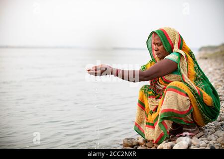 Une femme prie le long des rives de la rivière Gandak à Bihar, en Inde. Les hindous prient souvent sur les berges et les rives, car l'eau est considérée comme sainte. Banque D'Images